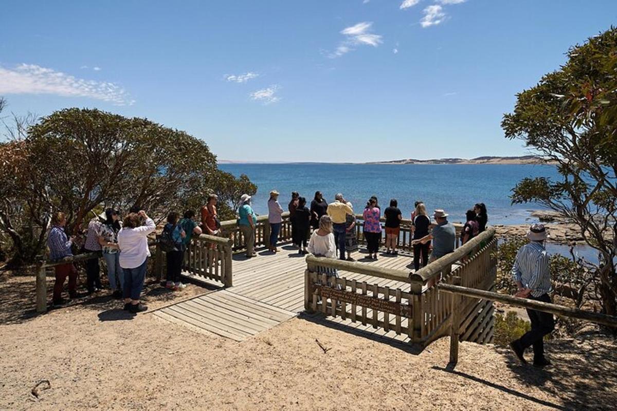 a group of people standing on a boardwalk near the water