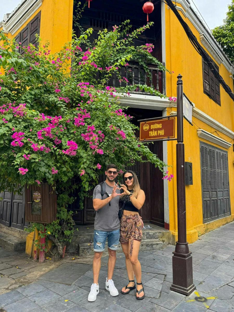 um homem e uma mulher parados em frente a um prédio amarelo