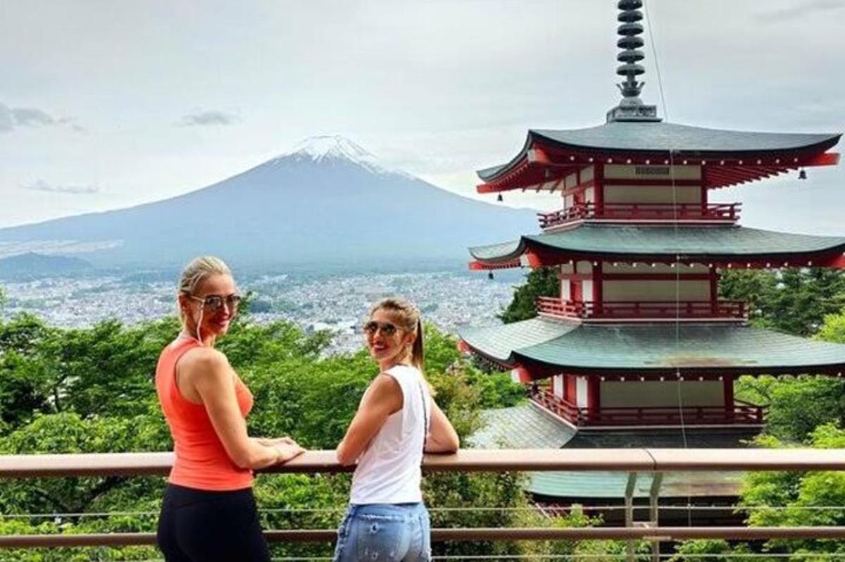 due donne in piedi su una recinzione di fronte a una pagoda