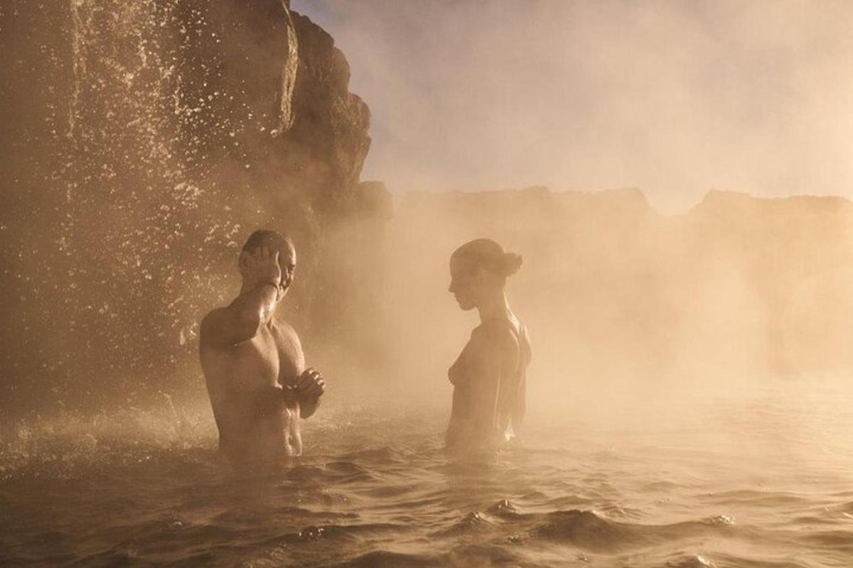 deux personnes debout dans l'eau près d'une cascade