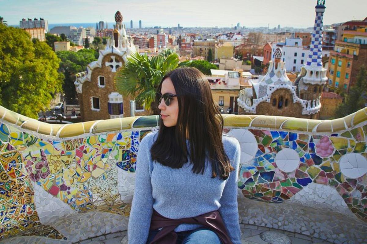 Una mujer sentada en una cornisa frente a una pared de mosaico.