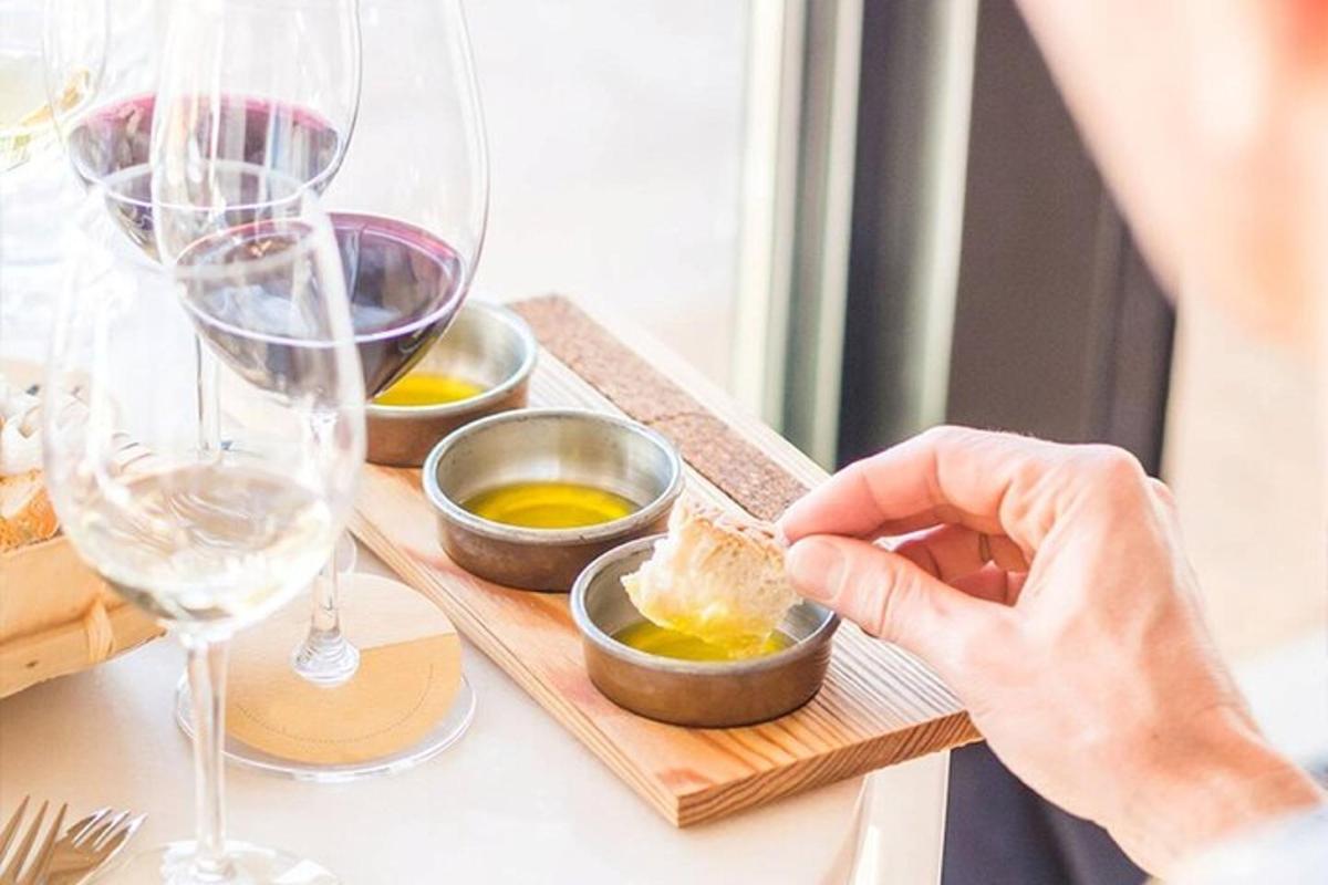 a person holding a piece of cheese in a bowl with wine glasses