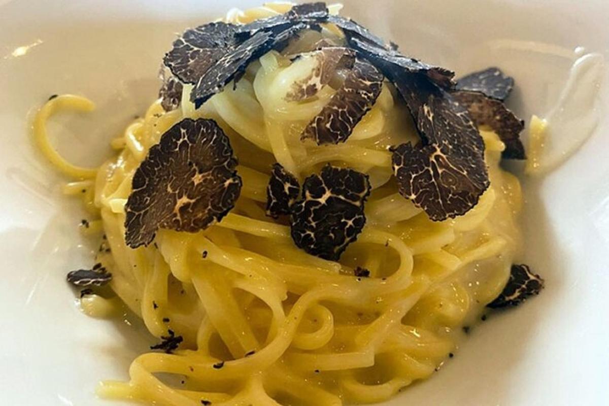a white plate of pasta with a garnishment on it