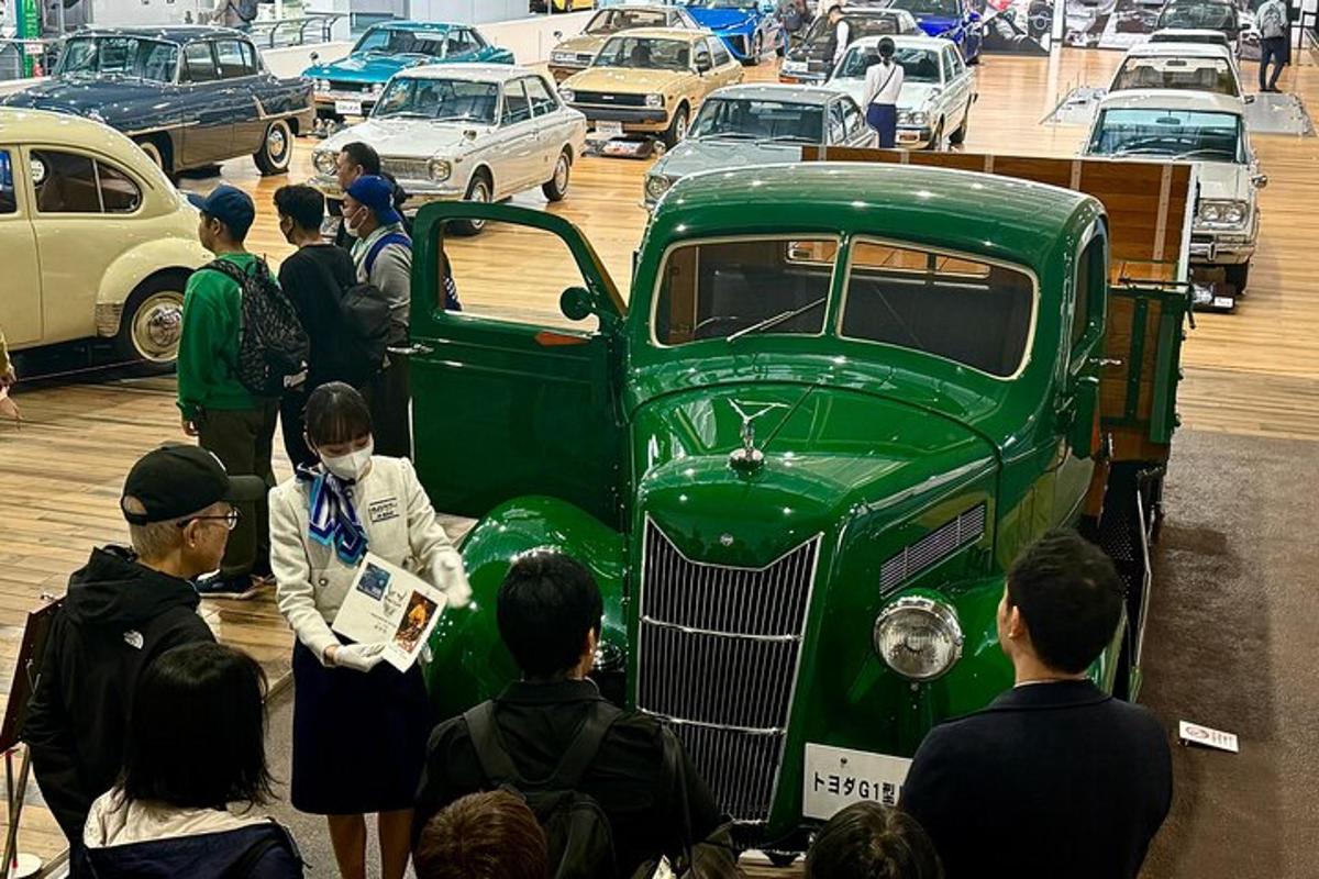 a group of people looking at an old green truck