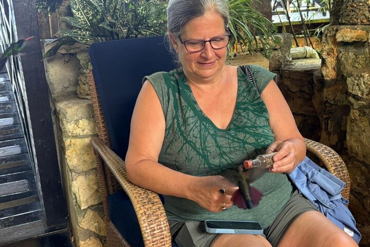 Una mujer sentada en una silla de mimbre mirando su teléfono celular.