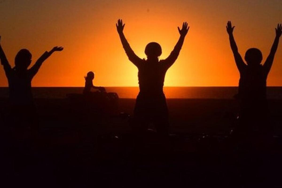 a group of people with their arms up at the sunset