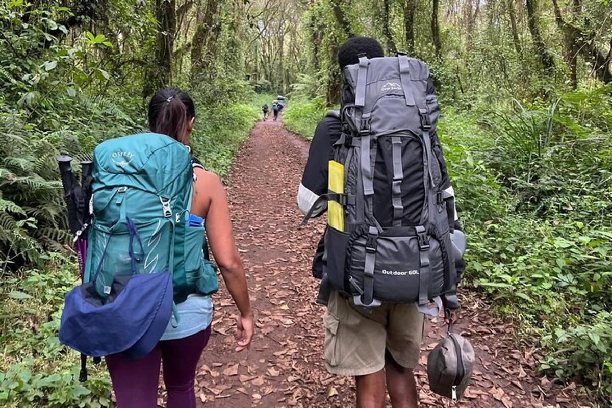 two people with backpacks walking down a dirt trail