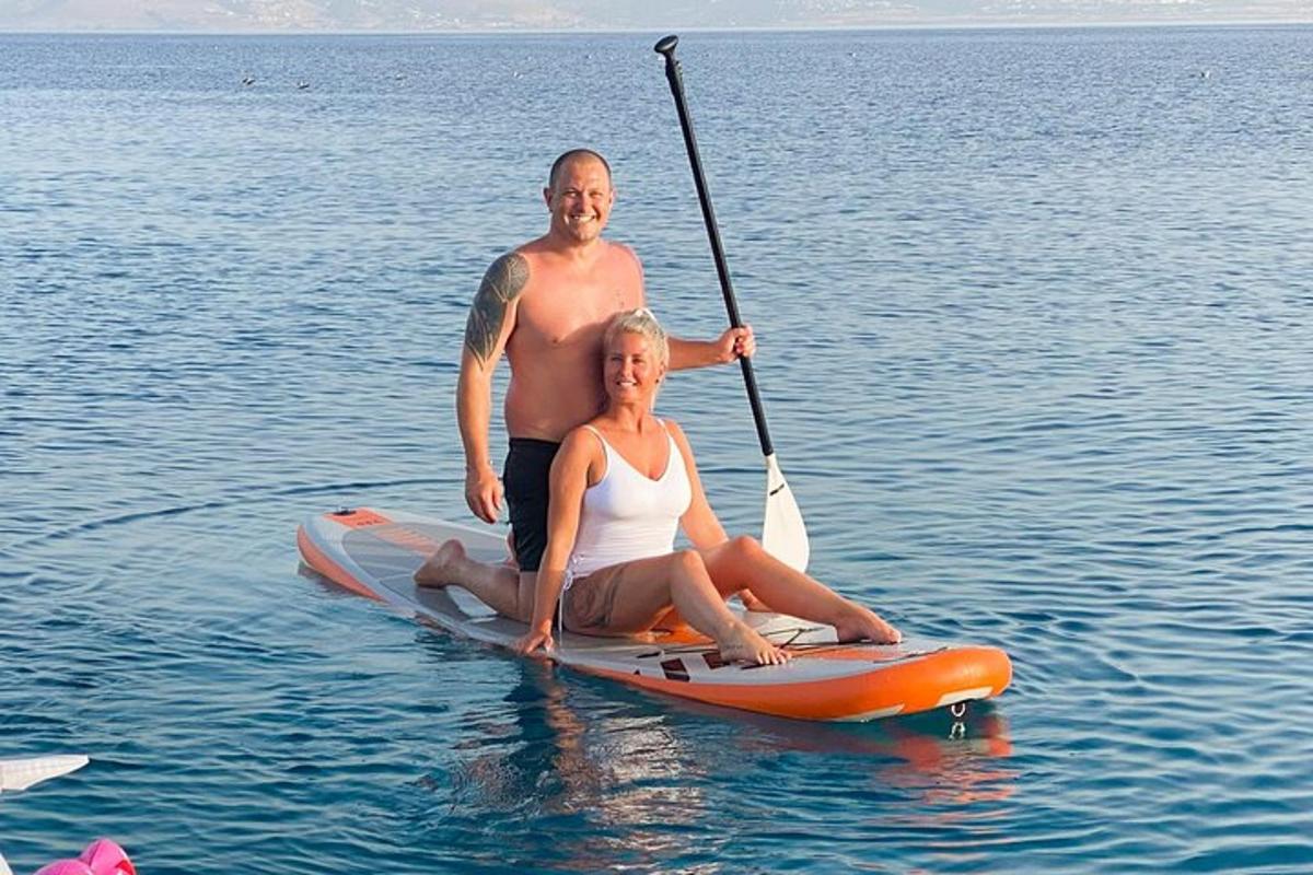 muž a žena sedící na paddleboardu ve vodě