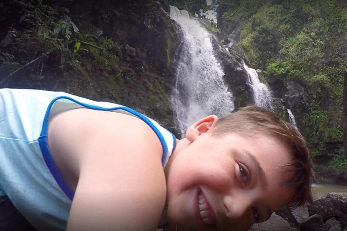 uma jovem em frente a uma cachoeira