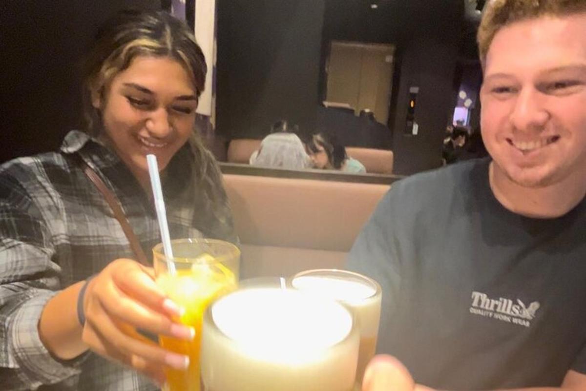 en mann og en kvinne som sitter ved et bord med en drink