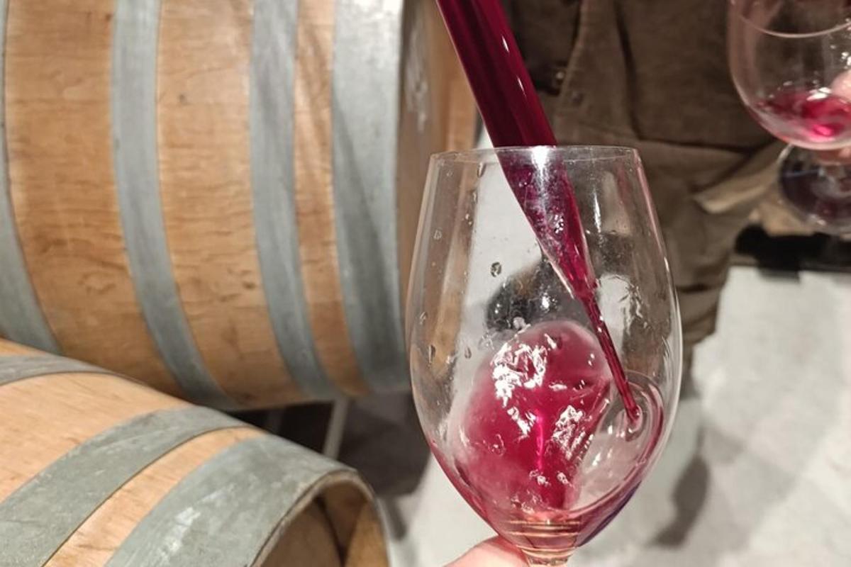 o persoană toarnă vin roșu într-un pahar de vin