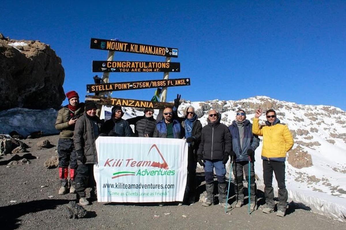 a group of people standing next to a sign on a mountain