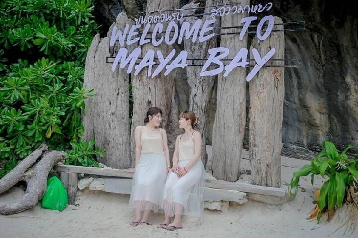 two women sitting on a bench in front of a sign