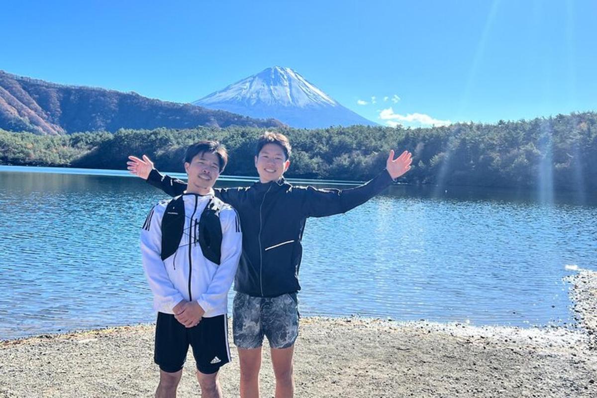 two boys standing next to a lake with a mountain in the background