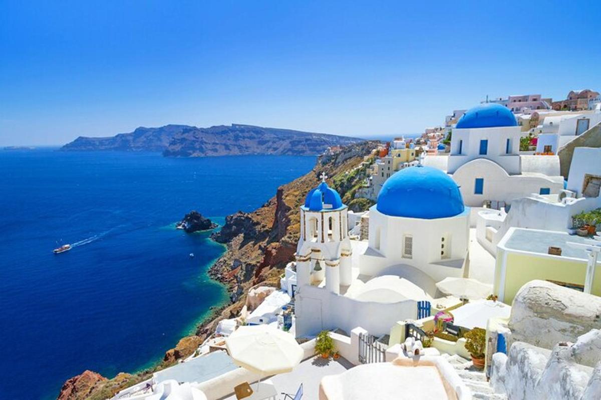 μια ομάδα λευκών κτιρίων με μπλε θόλους και τον ωκεανό