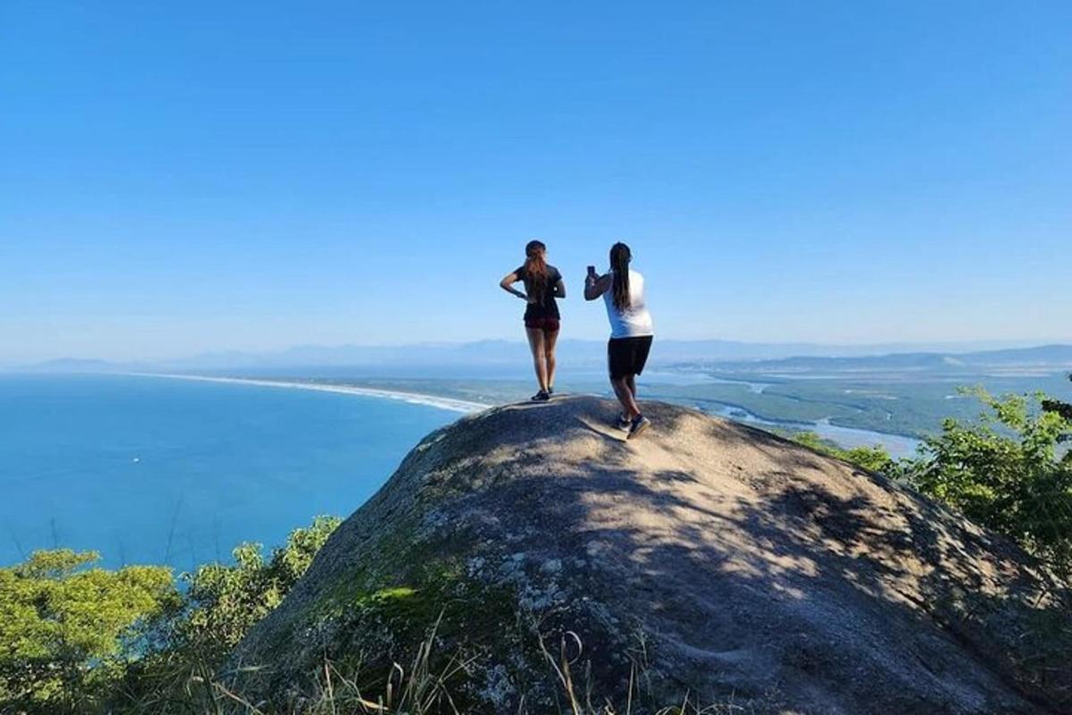 dva lidé stojící na vrcholu skály s výhledem na oceán