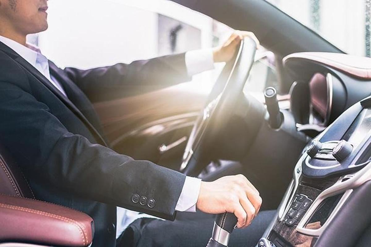 un uomo in giacca e cravatta alla guida di un'auto
