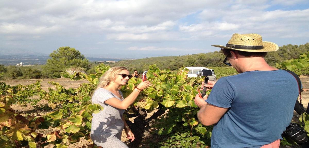 a man taking a picture of a woman in a vineyard