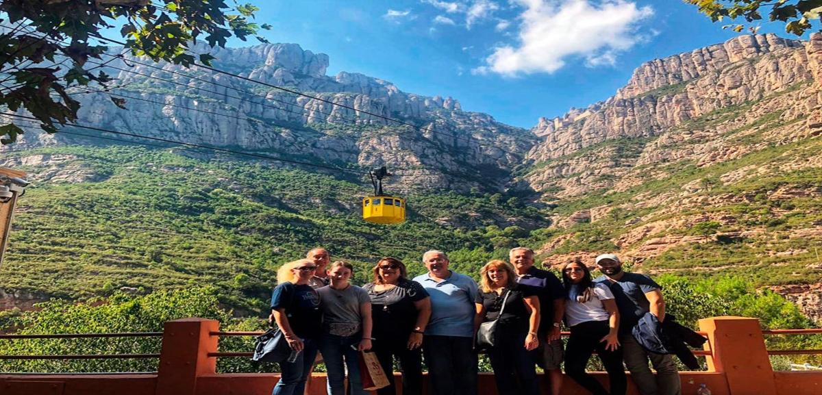 μια ομάδα ανθρώπων που στέκονται μπροστά στα βουνά