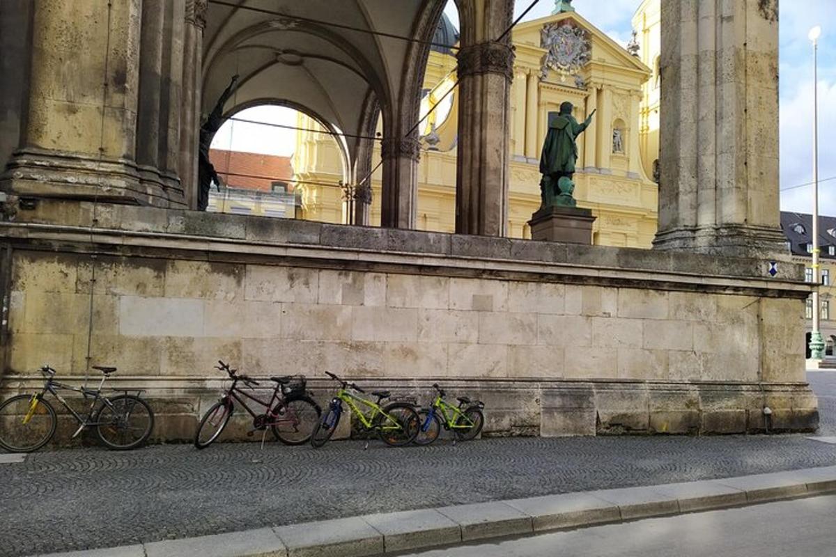 um grupo de bicicletas estacionadas contra um prédio com uma estátua