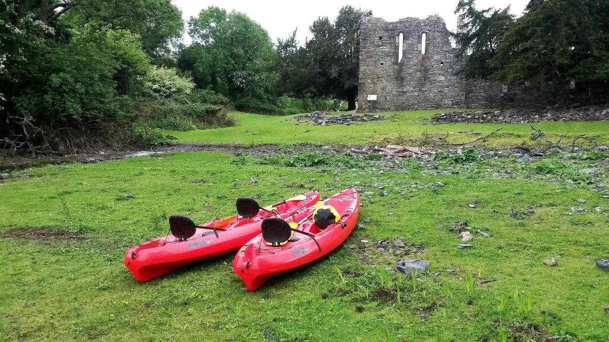 zwei rote Kajaks sitzen auf dem Gras in der Nähe einer Burg