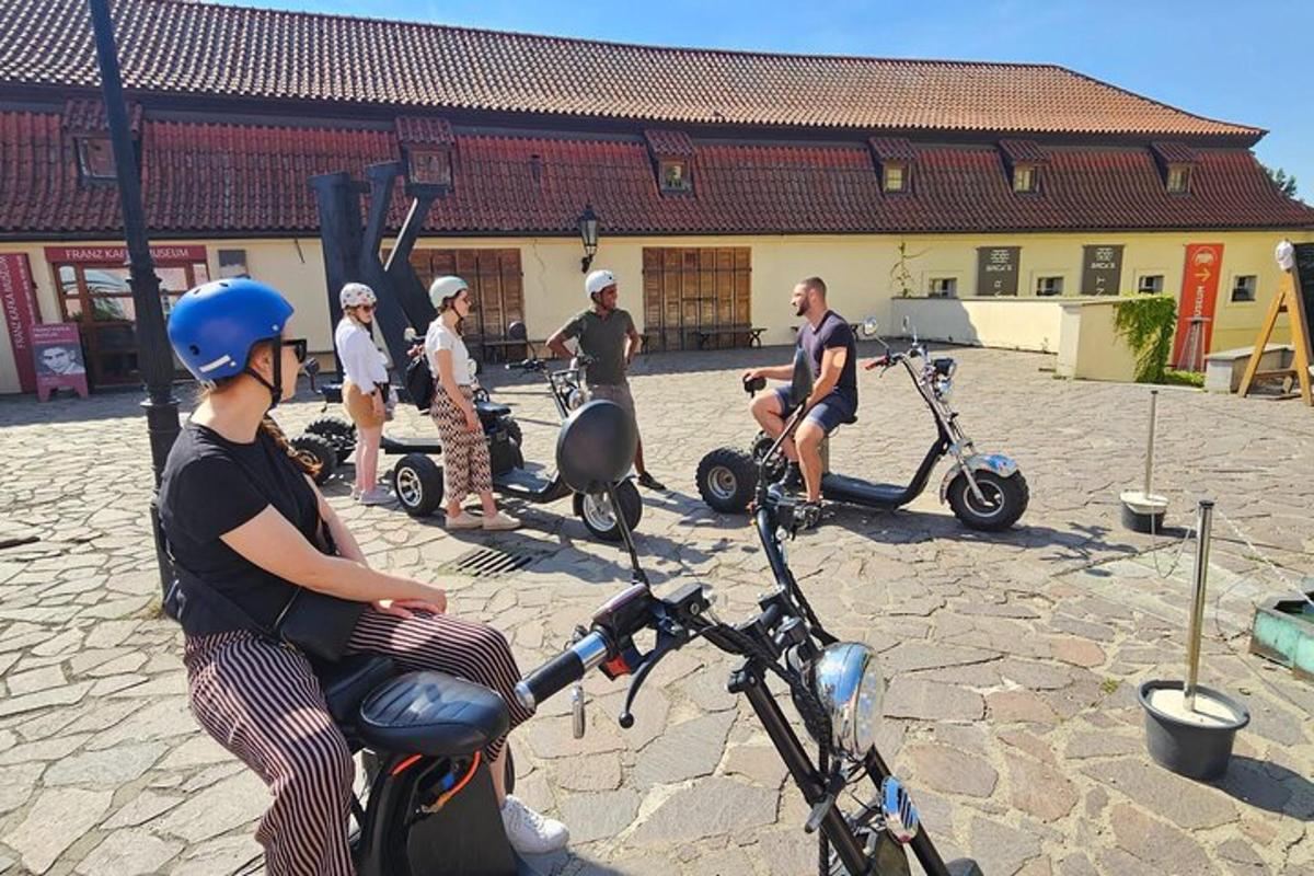 egy csoport ember robogókon ül egy épület előtt
