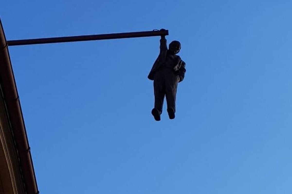 en mann som henger fra en stang på himmelen