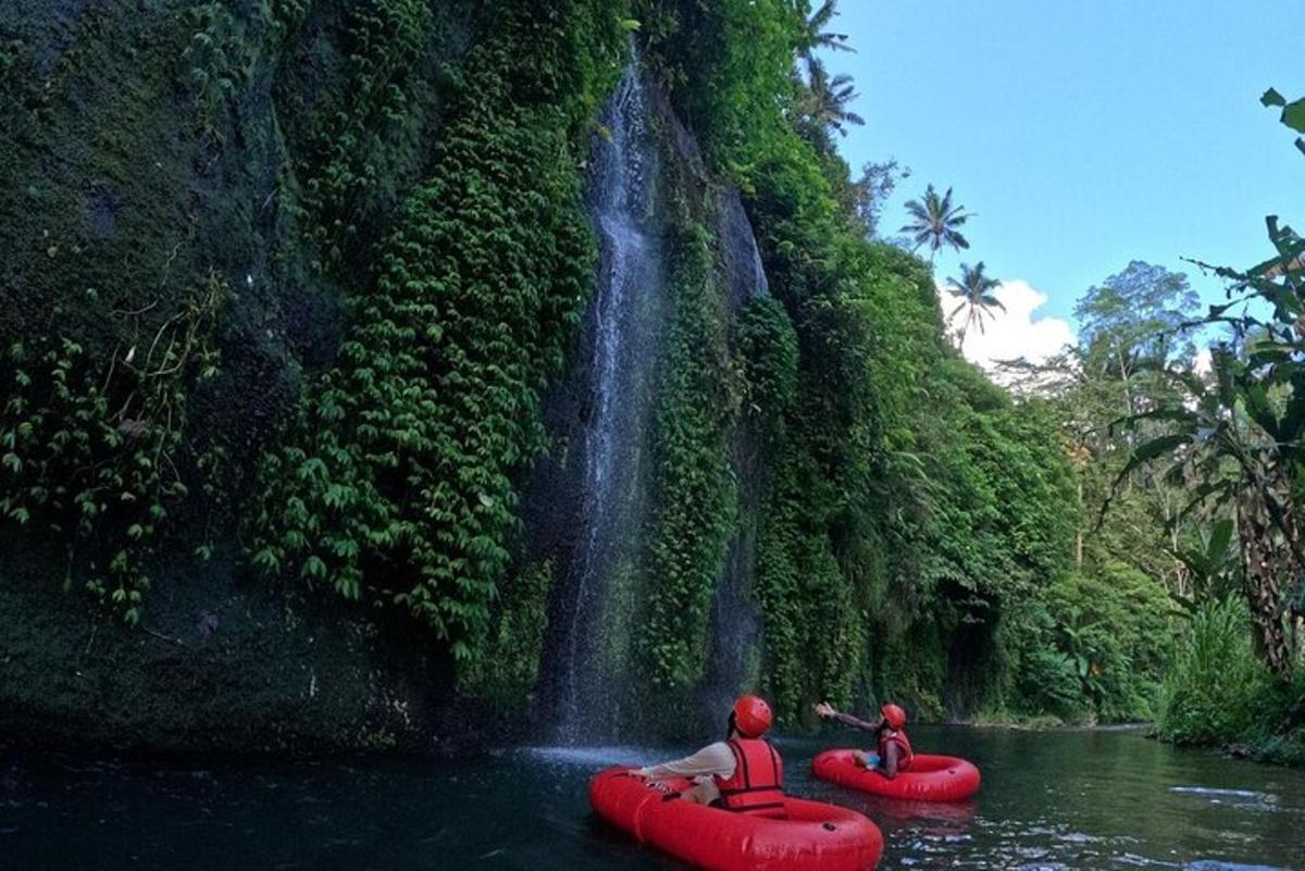 dua orang di rakit merah di depan air terjun