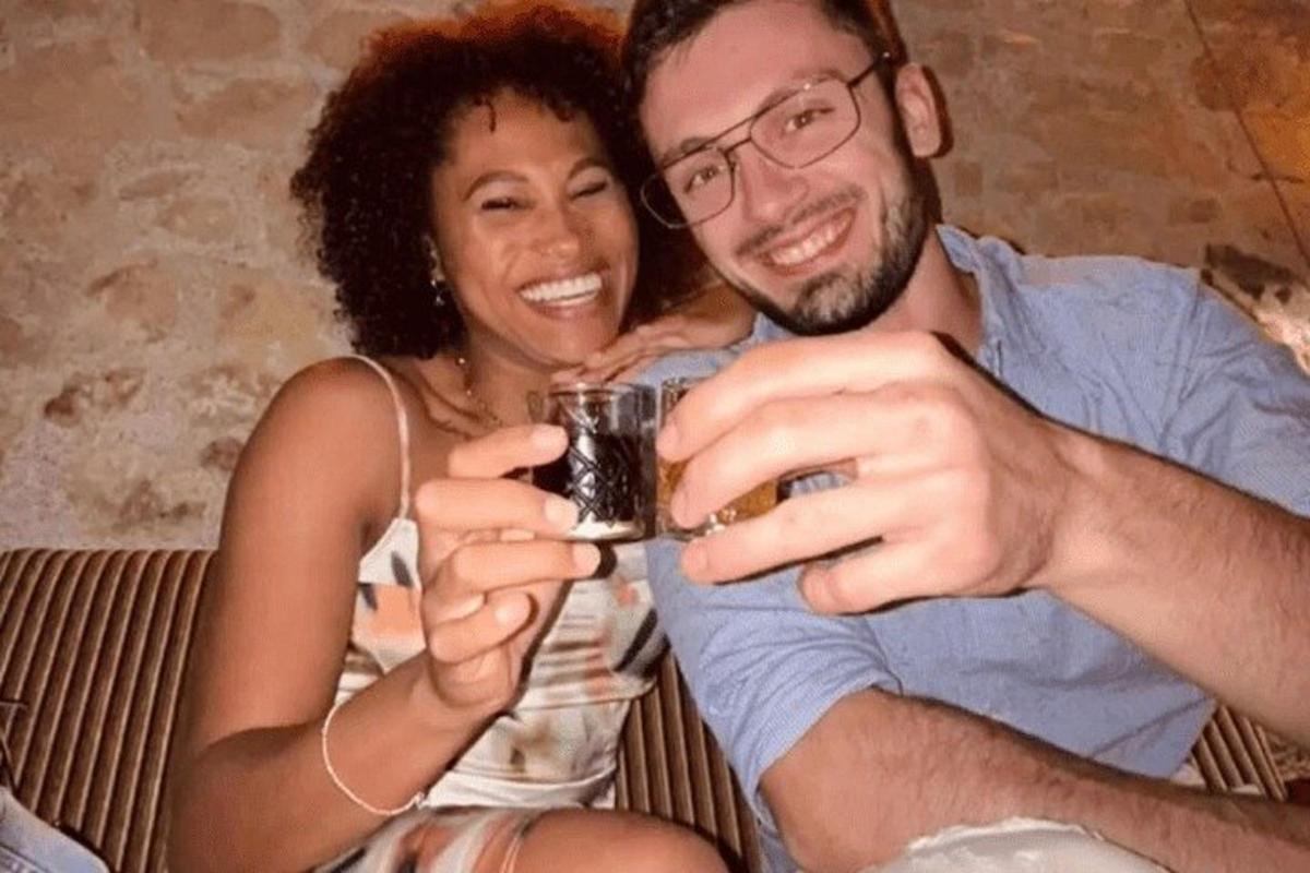un uomo e una donna seduti su un divano che tengono in mano un drink