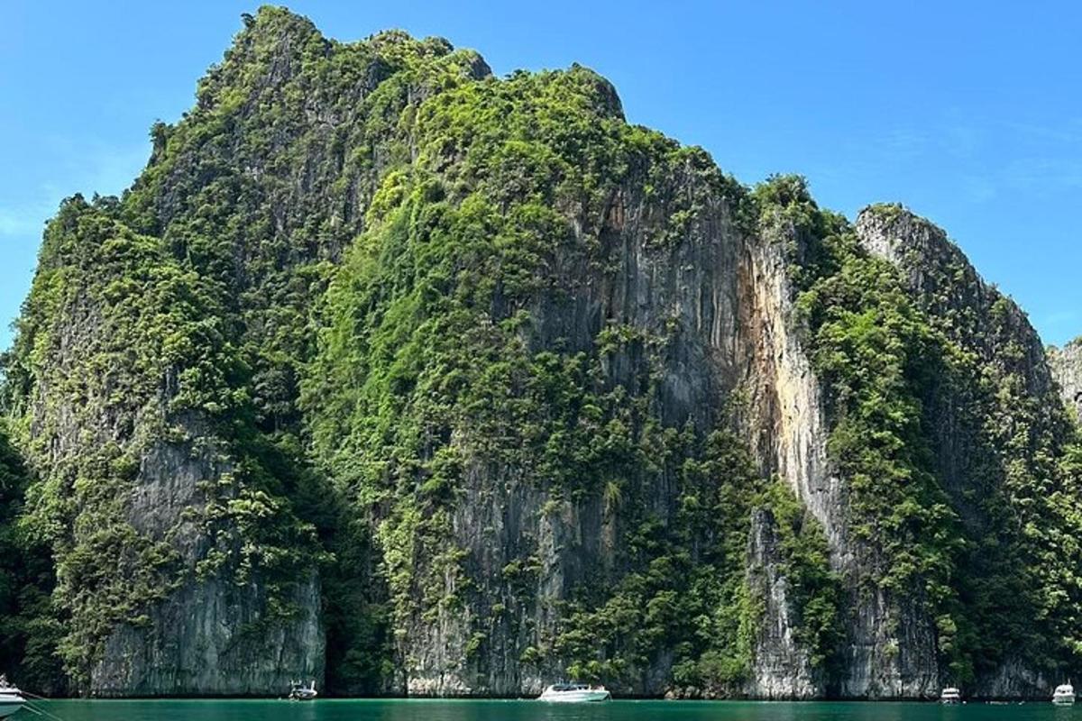 isang malaking mabatong bundok na may berdeng tubig at mga bangka