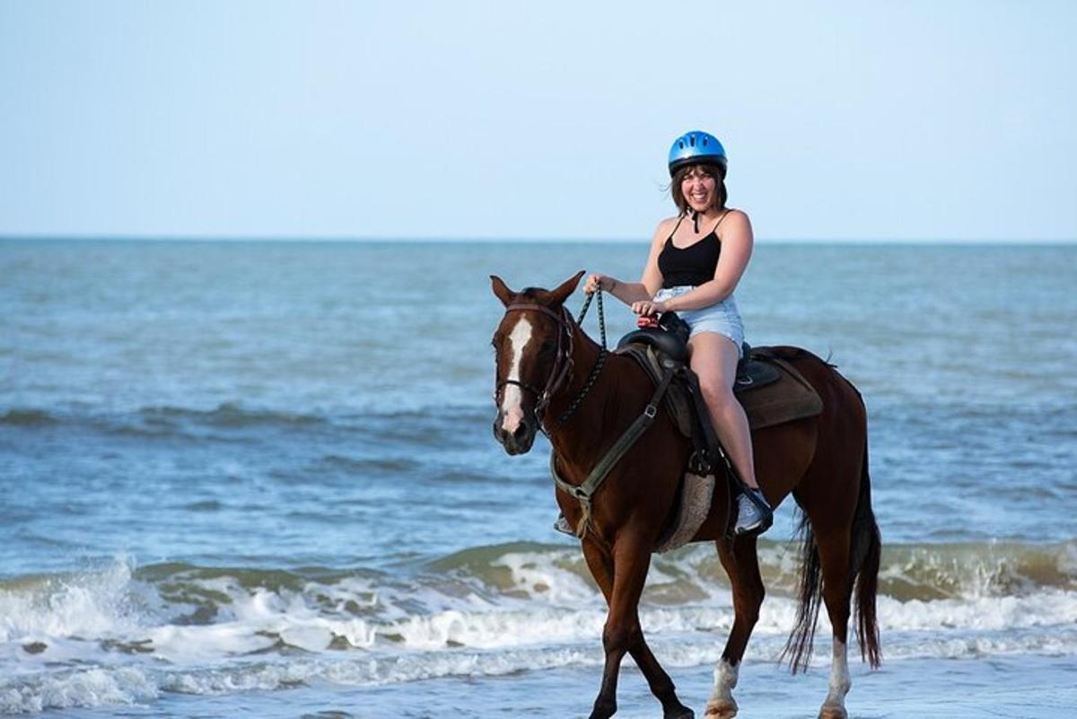 uma mulher cavalgando na praia
