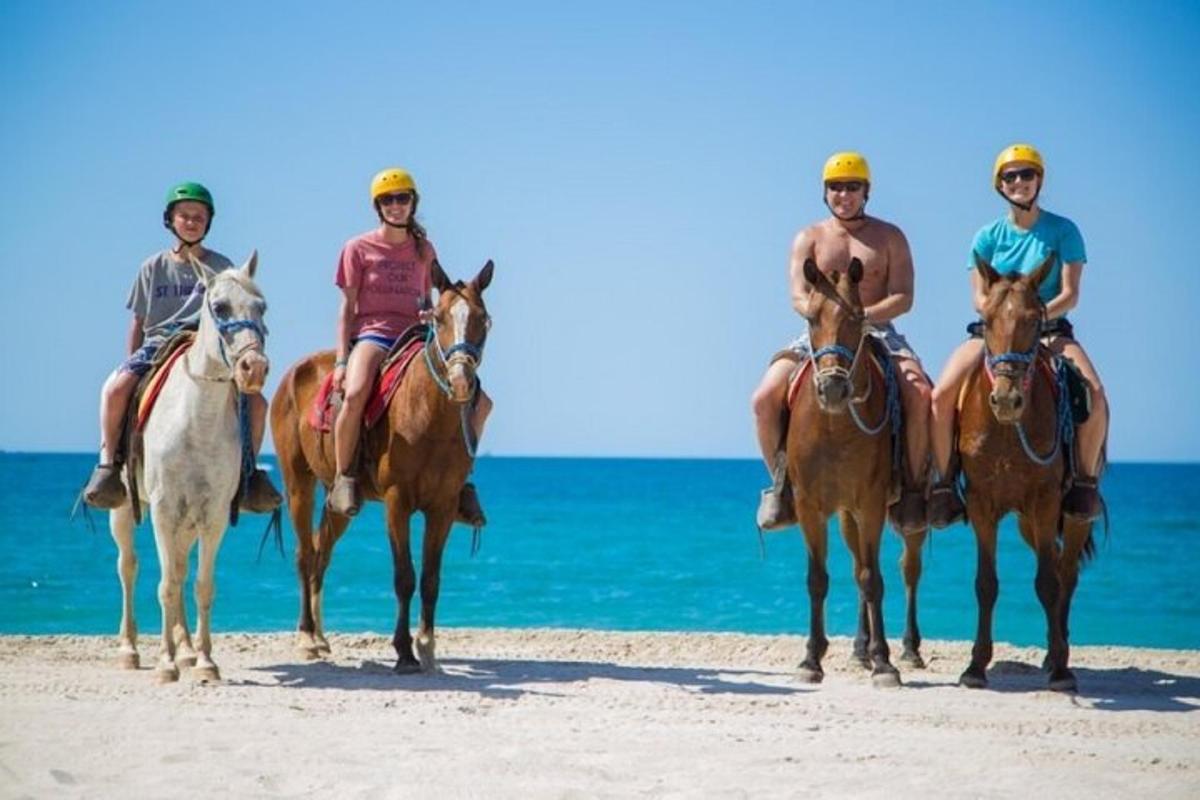 um grupo de pessoas andando a cavalo na praia