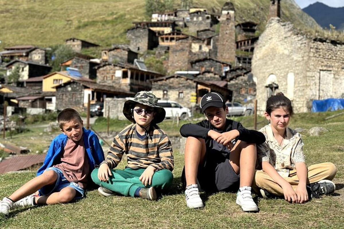 quattro giovani seduti sull'erba davanti a un villaggio