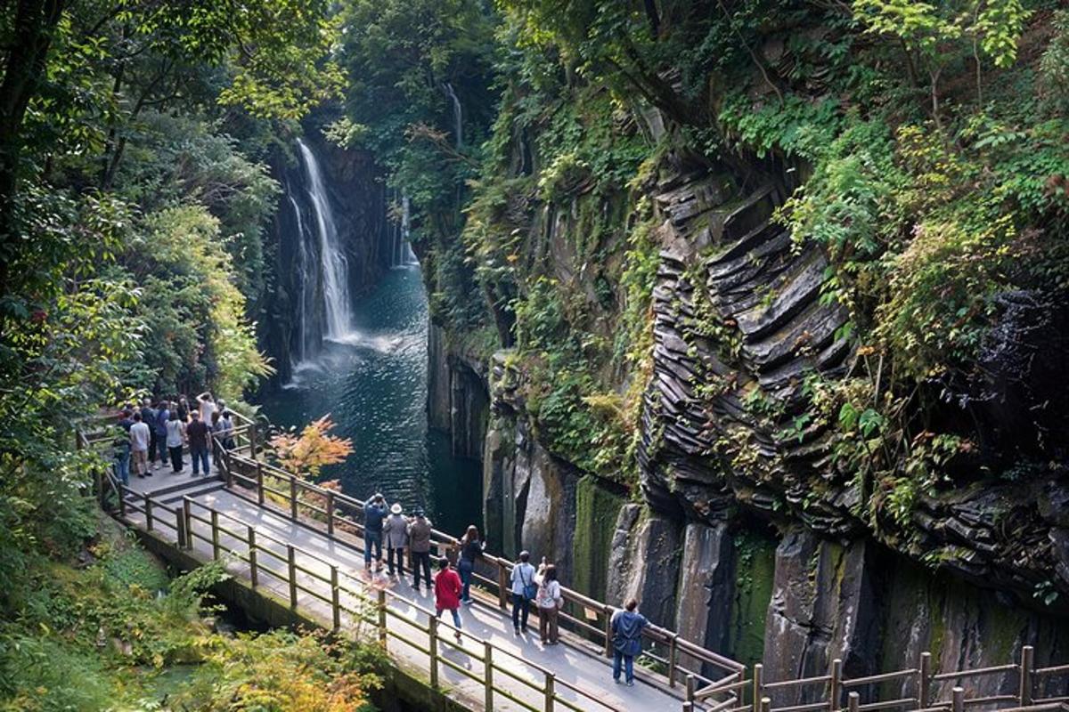 a group of people standing on a bridge near a waterfall