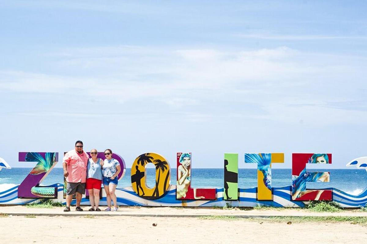 tre persone in piedi davanti a un cartello sulla spiaggia