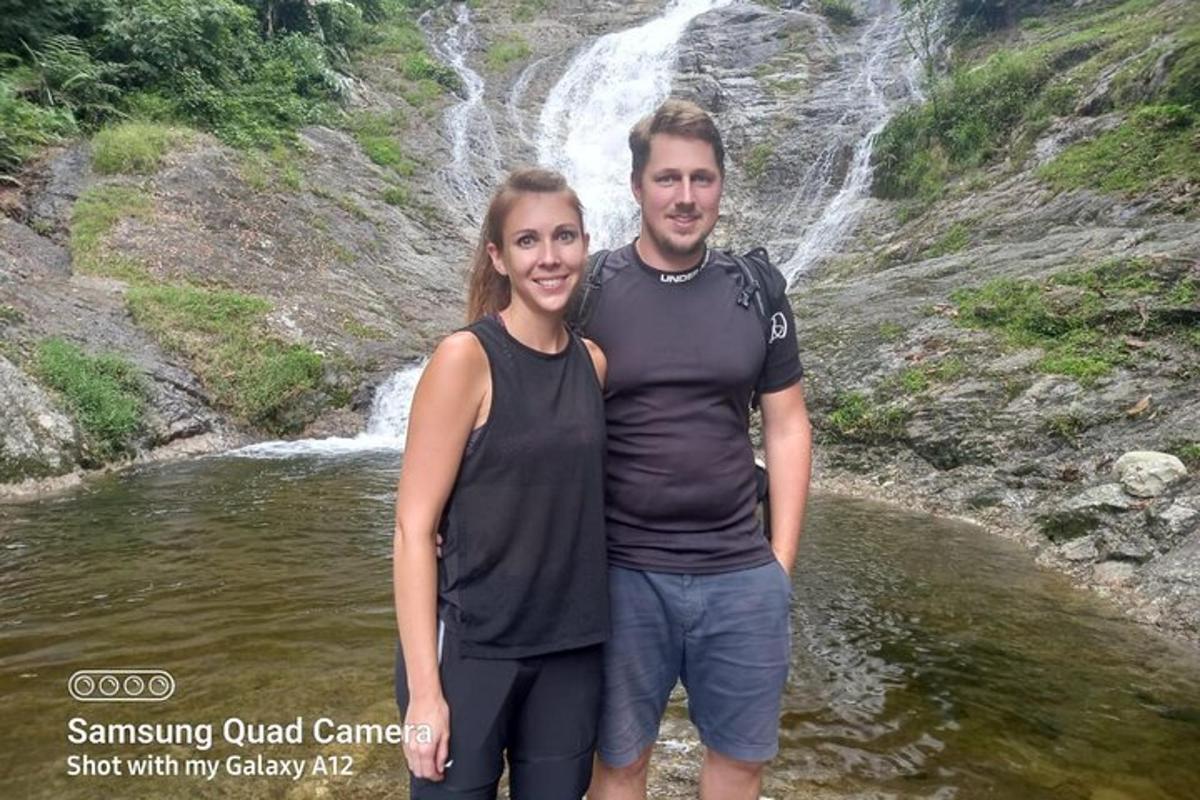 a man and a woman standing in front of a waterfall