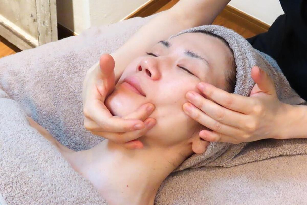 una donna sdraiata su un letto con le mani sul viso