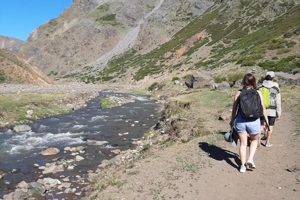 two people walking down a trail near a river