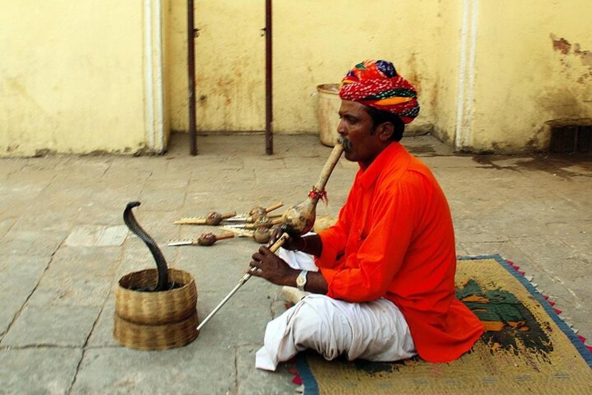 seorang pria duduk di tanah sambil memainkan alat musik