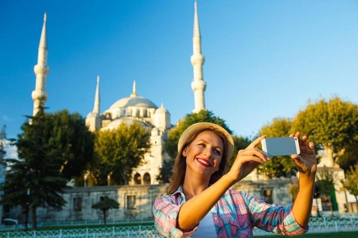 isang babaeng kumukuha ng larawan ng isang mosque gamit ang kanyang cell phone