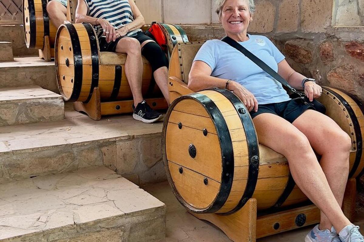 ženska, ki sedi na klopi s sodi vina