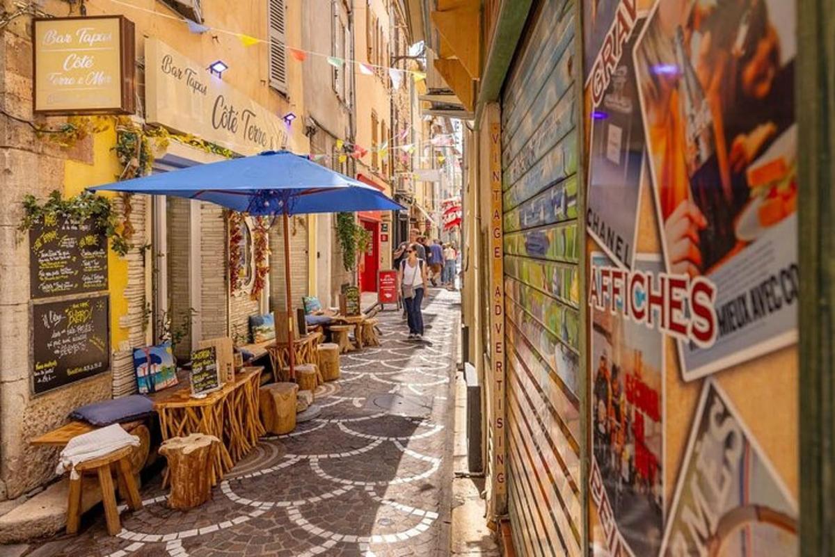 eine Gasse mit einem blauen Sonnenschirm und Tischen und Stühlen