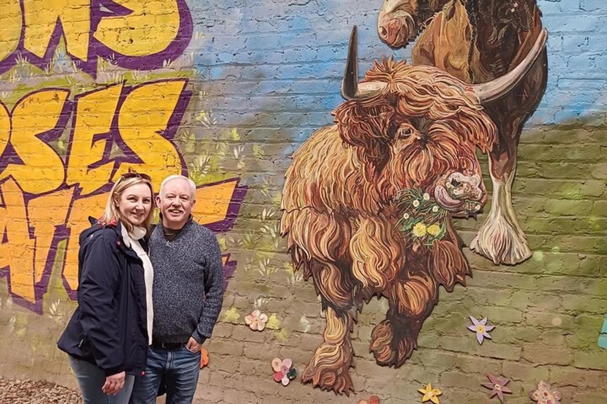 a man and woman standing in front of a wall with a painting of a buffalo