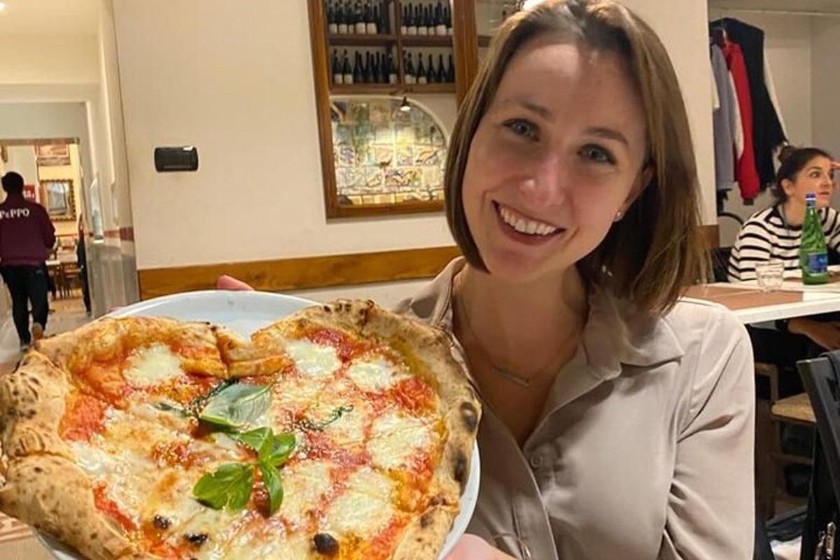 žena sedící u stolu s pizzou