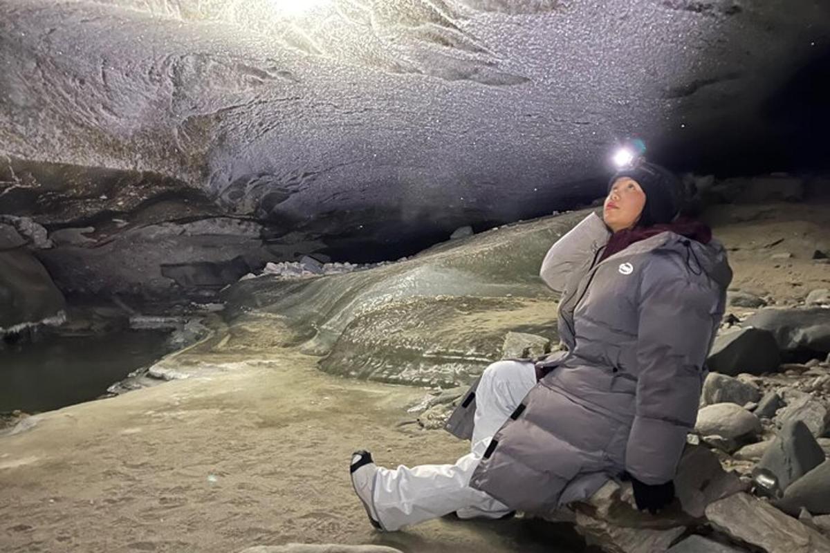 kona situr á jörðinni við hliðina á íshelli