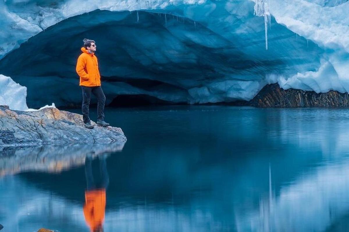Un hombre parado sobre una roca frente a un iceberg.