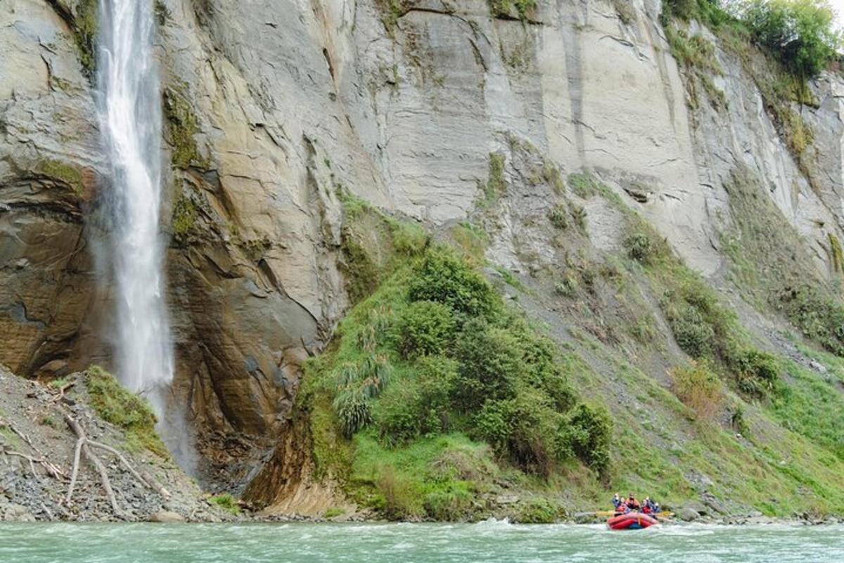 eine Gruppe von Menschen auf einem Floß vor einem Wasserfall