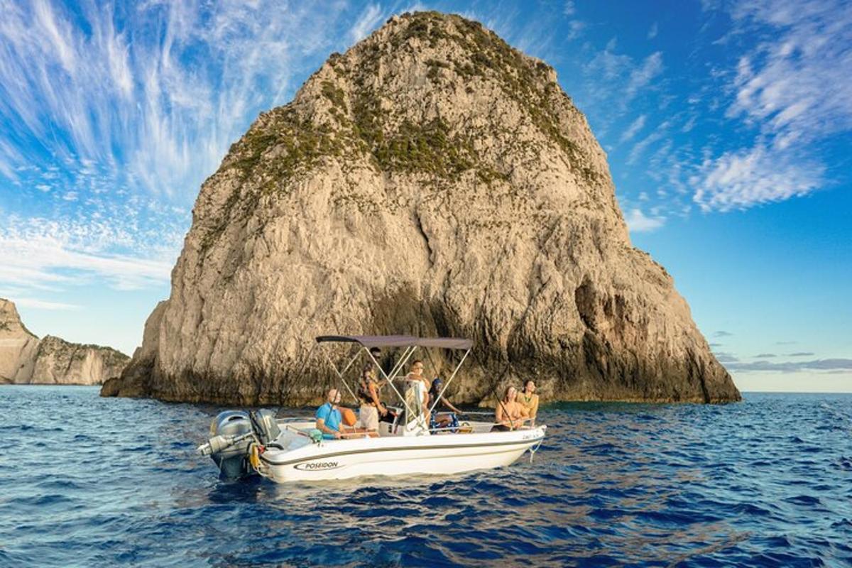 a group of people on a boat in front of a rock
