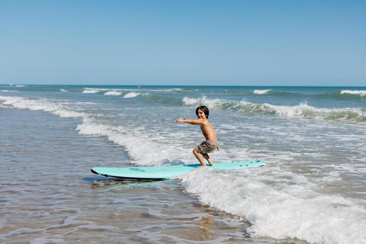 en ung gutt som står på et surfebrett i havet