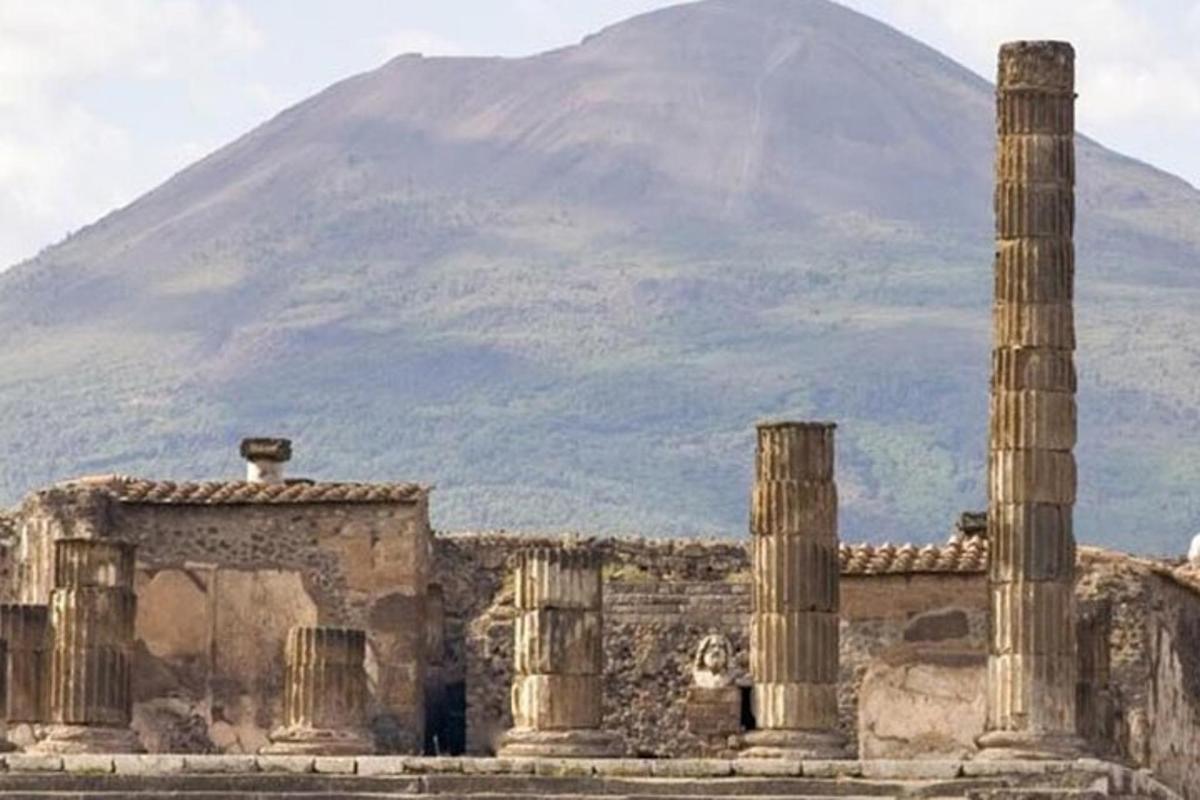 an ancient building with columns and a mountain in the background